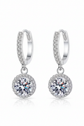 Close-up of The Stella drop earrings featuring a brilliant moissanite center stone in a round pavé halo, suspended from a silver huggie hoop.