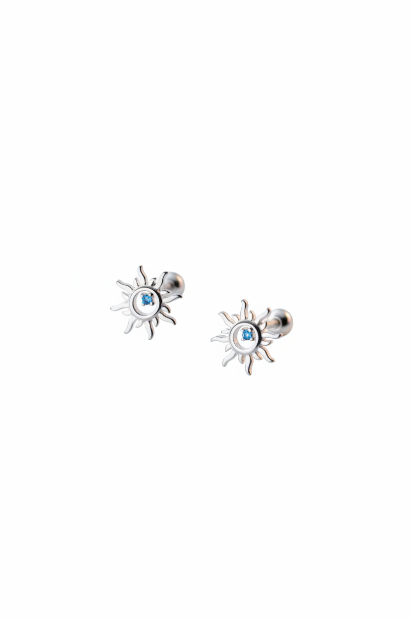 Macro shot of The Solis Azure Stud earrings, showcasing the sunburst silver design and a brilliant blue zircon center stone.