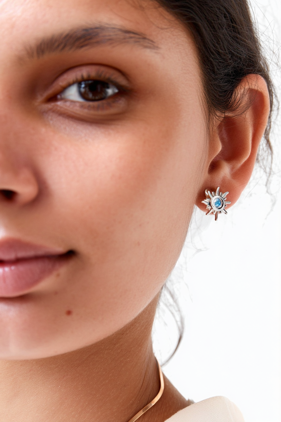 Macro shot of The Solis Azure Stud earrings, showcasing the sunburst silver design and a brilliant blue zircon center stone.