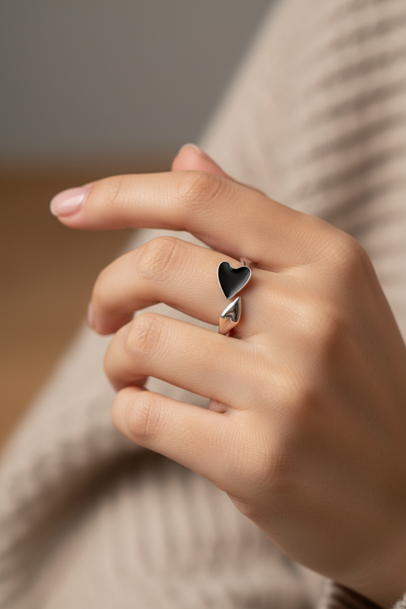 Minimalist 925 sterling silver ring featuring a central black heart-shaped emblem, handcrafted vintage-style jewelry by Nura Label.