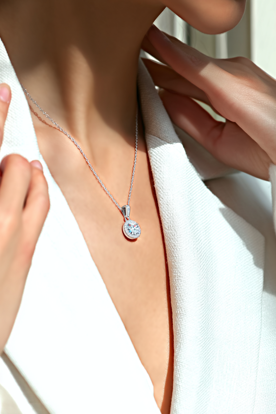 Close-up of The Lyra pendant, featuring a brilliant 1.0 carat round-cut moissanite inside a classic round pavé halo in solid 925 silver.
