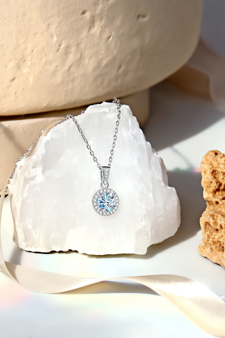 Close-up of The Lyra pendant, featuring a brilliant 1.0 carat round-cut moissanite inside a classic round pavé halo in solid 925 silver.